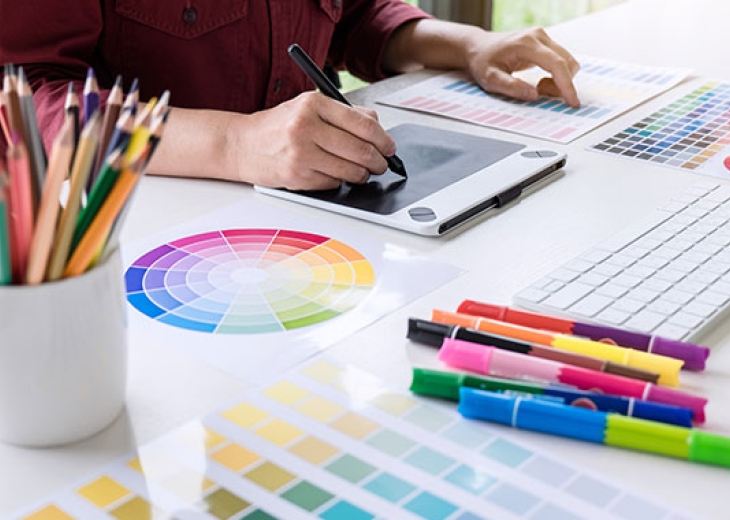 Image of female creative graphic designer working on color selection and drawing on graphics tablet at workplace.