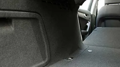 Empty car trunk with dark gray carpet lining and folded-down rear seats, creating a flat surface.