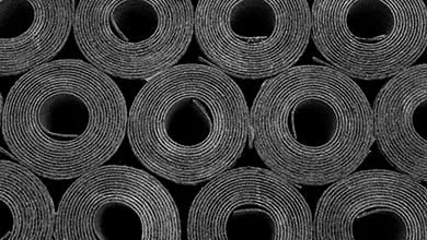 Black and white, close-up of stacked industrial material rolls, forming concentric circles.
