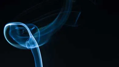 Wispy blue smoke swirling into a loop against a black background.