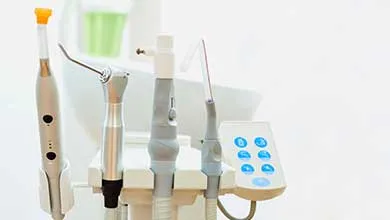 Dental equipment tools mounted on a clinical workstation, including handpieces, tubing, and digital control panel.