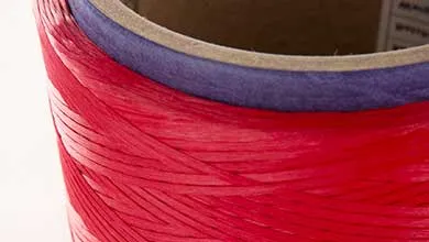 red yarn on a purple spool on a white background