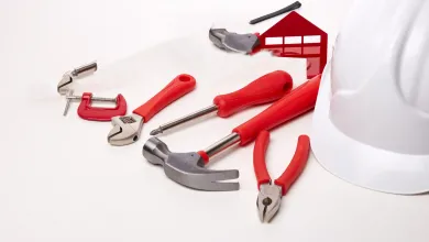 Construction hand tools and a white safety helmet placed next to each other.
