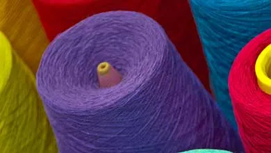 Close-up of large spools of yarn in bright colors, including purple, teal, yellow, red, and blue
