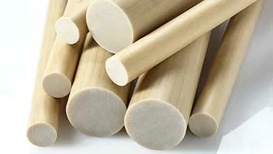 Close-up of several tan cylindrical rods of different sizes stacked on a white surface.